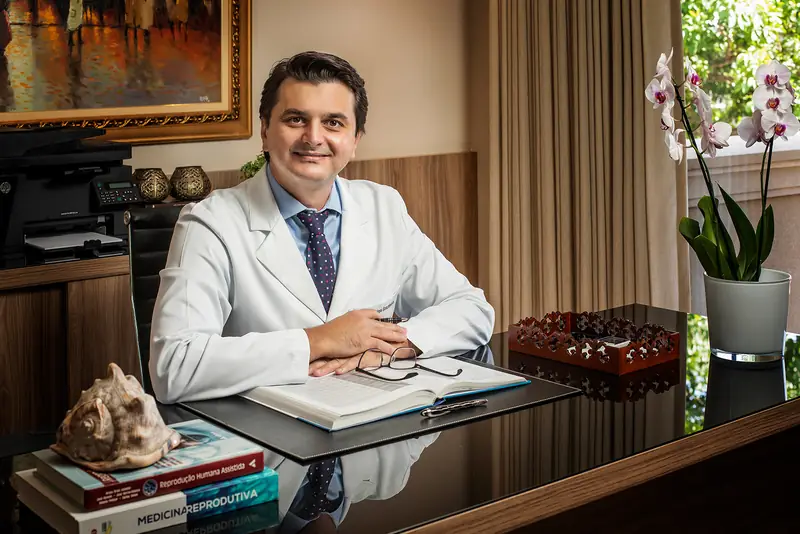 Médico de jaleco sentado à mesa do consultório